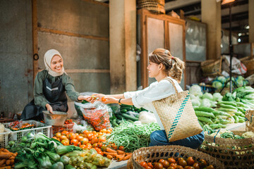 greengrocery seller receiving vegetables that customer buying from her