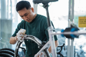 young man cleaning bicycle tire with foaming soap with indoor background