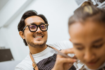 happy asian hairdresser doing his job at barbershop close up view