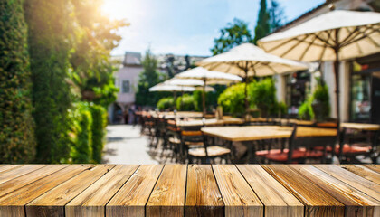 Empty wooden table with a blurred cafe terrace in the background, inviting and ideal for product presentation - obrazy, fototapety, plakaty
