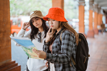 two women are confused when looking at a map for a tourist destination during a traveling trip
