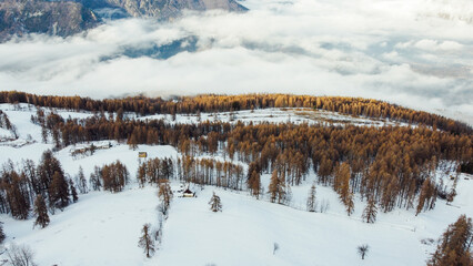 Fototapeta na wymiar Aerial view of winter landscape with mountain slopes covered with snow, fluffy clouds and coniferous forest. Natural background.