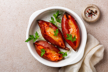 Baked stuffed sweet potato with cheese and butter. Top view, beige table surface.