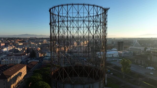 Alba sul Gazometro del quartiere post industriale Ostiense a Roma, Italia.
Veduta aerea con drone dei raggi del sole che passano attraverso la vecchia struttura del Gasometro.
