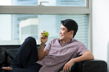 Healthy Asian man eating an apple.
