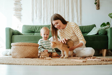 Mother and son with cat playing in the living room at home