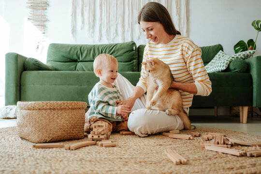 Mother holding cat and playing with son in the living room