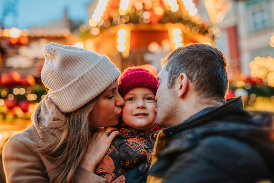 Father and mother kissing son at Christmas market