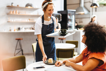 Friendly waitress serving a woman in a coffee shop