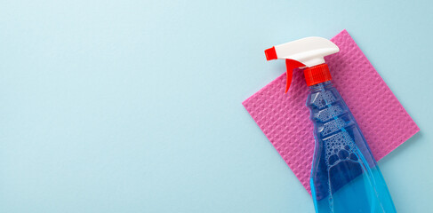 Embrace a spotless ambiance. Top view of dust rag, spray detergent on a light blue background....