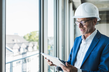 Smiling engineer using tablet PC near window