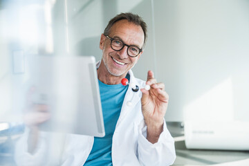 Happy senior man in lab coat holding tablet PC and molecular structure