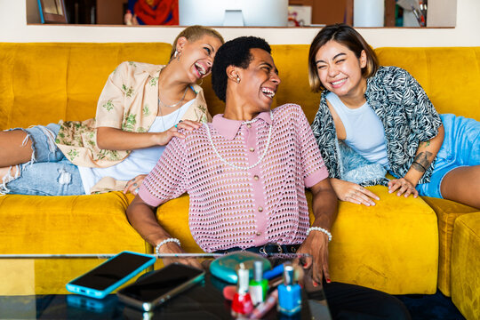 Group of friends bonding at home, LGBTQ and diversity concepts - Homosexual couple and fluid gender non binary young man with LGBT cross dressing clothing style having fun in the apartment