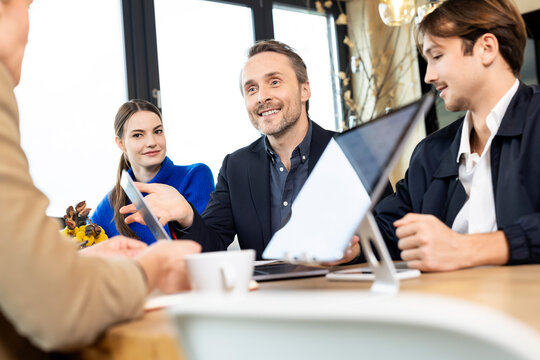 Smiling businessman discussing with colleagues in meting at workplace