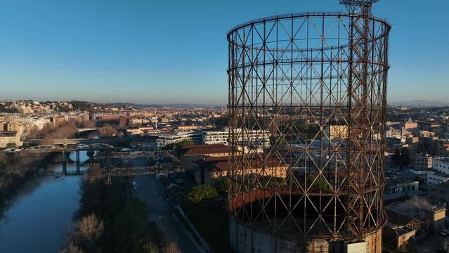 Alba sul Gazometro del quartiere post industriale Ostiense a Roma, Italia.
Veduta aerea con drone dei raggi del sole che passano attraverso la vecchia struttura del Gasometro.
