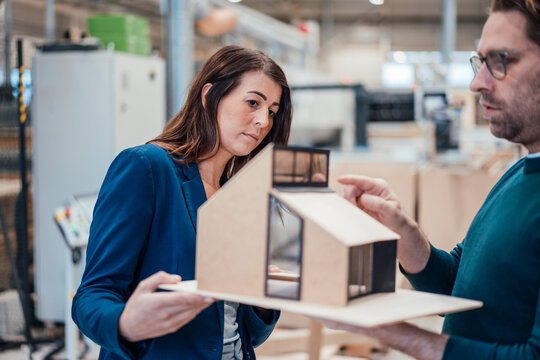 Architects examining model house standing in workshop
