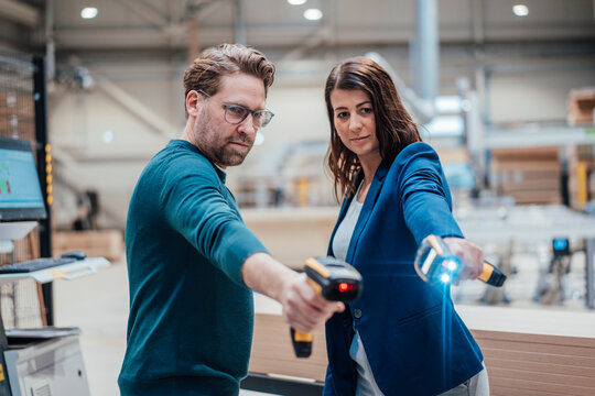 Colleagues with illuminated bar code readers standing in workshop