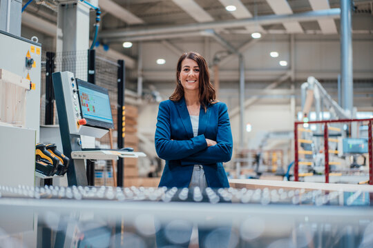 Smiling businesswoman with arms crossed by computer in industry