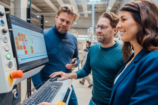 Smiling business colleagues working on computer in workshop