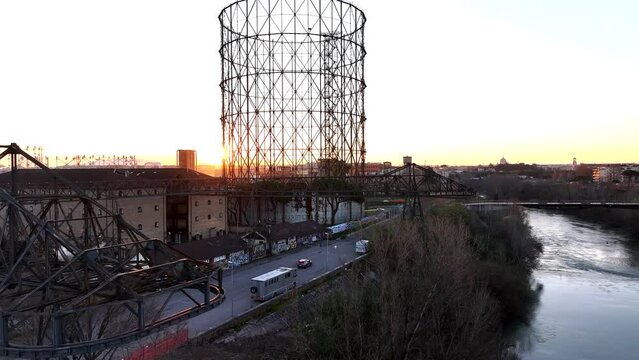Alba sul Gazometro del quartiere post industriale Ostiense a Roma, Italia.
Veduta aerea con drone dei raggi del sole che passano attraverso la vecchia struttura del Gasometro.

