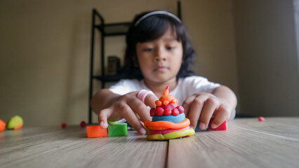 Little girl child sitting at table playing with play doh or plasticine at home, sensory indoor activities for toddlers. Creativity and play
