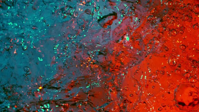 Super slow motion of splashing water illuminated by neon lights. Filmed on high speed cinema camera, 1000 fps.