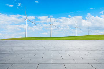 Empty square floor and green grass with wind turbine under blue sky