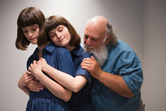 Loving father consoling two twin daughters