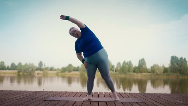 Tired overweight woman exercising near lake working hard to lose weight, fitness