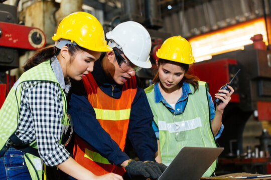 Asian engineer or technician man foreman training female trainee using program or system in industry manufacturing factory. teamwork and corporate people working hard in industrial construction site