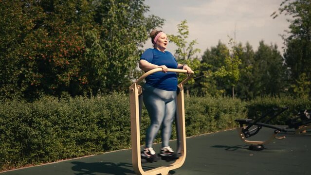 Tired plus size woman exercising on air walker on sunny street workout ground