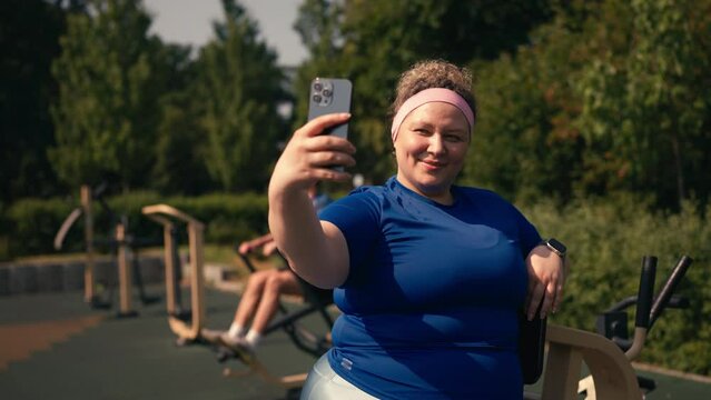 Cheerful plump woman posing for selfie at sports ground, active lifestyle