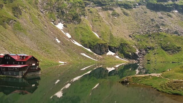 Panning video of old cabin and Balea Lake on transfagarasan mountain road.
