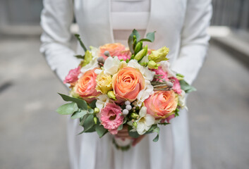 Tender hands cradle a bridal bouquet