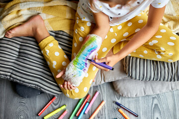 Teen girl with a broken arm at home draws an orthopedic cast