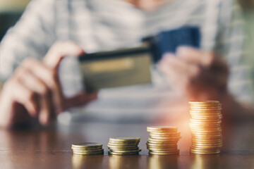 For BNPL, Buy Now Pay Later, concept. Stack of coins with blurred woman choose on of credit card for payment