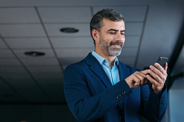 Obraz na płótnie Canvas Businessman using smartphone in office