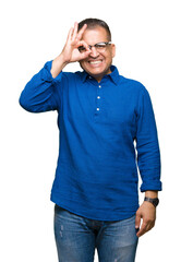 Middle age arab man wearing glasses over isolated background doing ok gesture with hand smiling, eye looking through fingers with happy face.