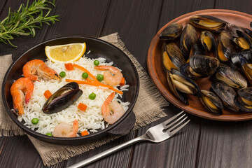 Shrimps and mussels with rice in frying pan. Mussels on plate