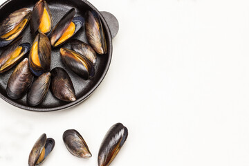 Shellfish Mussels in frying pan. Mussels are scattered on table