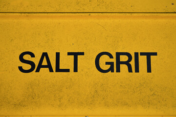 Salt Grit sign on yellow container at side of road with slope. protection for road surface during cold icy weather conditions 