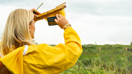 Unrecognizable woman taking bee comb picture with smartphone