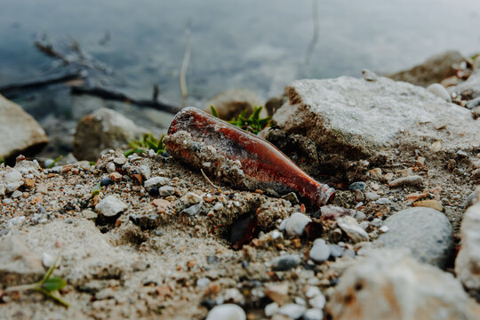 A discarded bottle pollutes a natural lakeside illustrating environmental neglect and the need for conservation