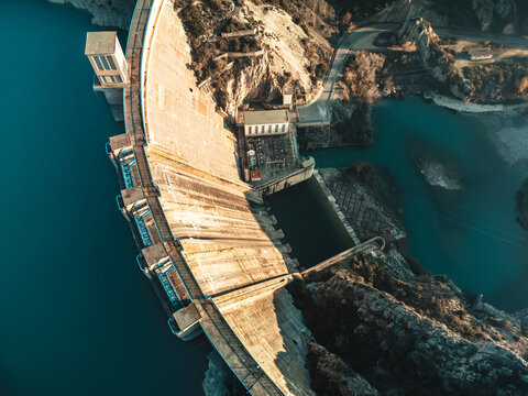 Top view dramatic aerial perspective of a dam casting long shadows across the water at sunrise or sunset