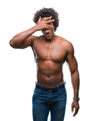 Afro american shirtless man showing nude body over isolated background peeking in shock covering face and eyes with hand, looking through fingers with embarrassed expression.