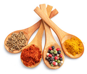 Colorful different seasonings in wooden spoons isolated on white background.