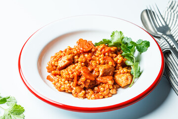 Ptitim with chicken, vegetables and cilantro, white background. Traditional Israeli food.