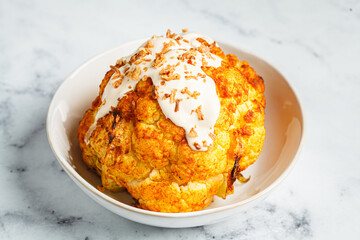Whole roasted spicy cauliflower with tahini dressing and caramelized onions.