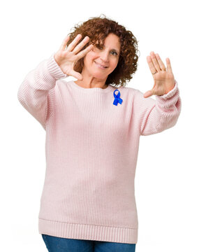 Middle ager senior woman wearing changeable blue color ribbon awareness over isolated background Smiling doing frame using hands palms and fingers, camera perspective