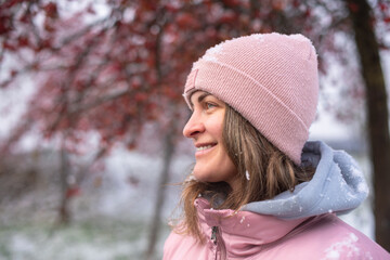 Winter Elegance: Portrait of a Beautiful Girl in a Snowy European Village. Winter lifestyle portrait of cheerful pretty girl. Smiling and having fun in the snow park. Snowflakes falling down